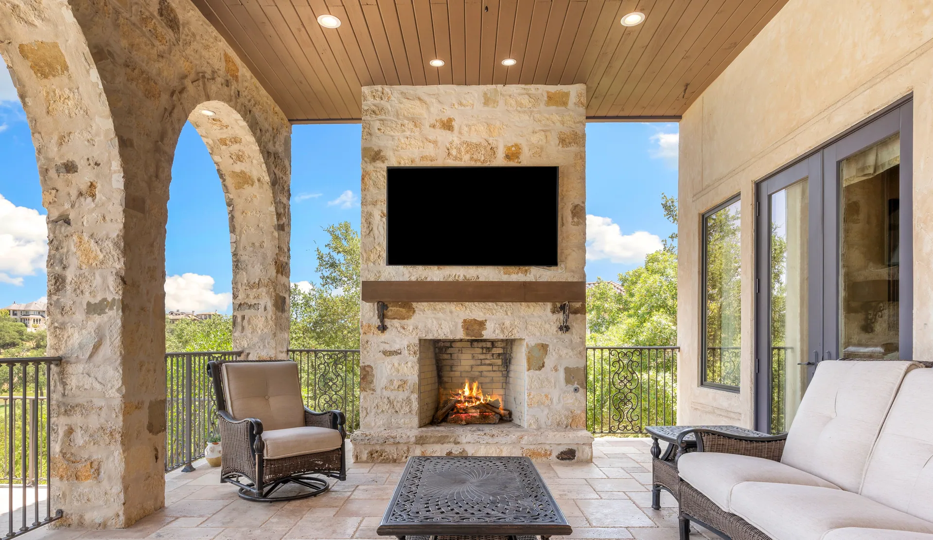 Covered patio with a stone outdoor fireplace and TV
