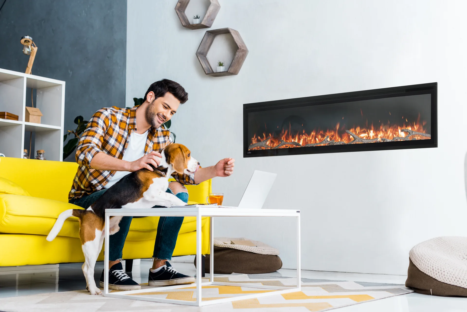Man and a beagle on a sofa beside a wall-mounted linear fireplace
