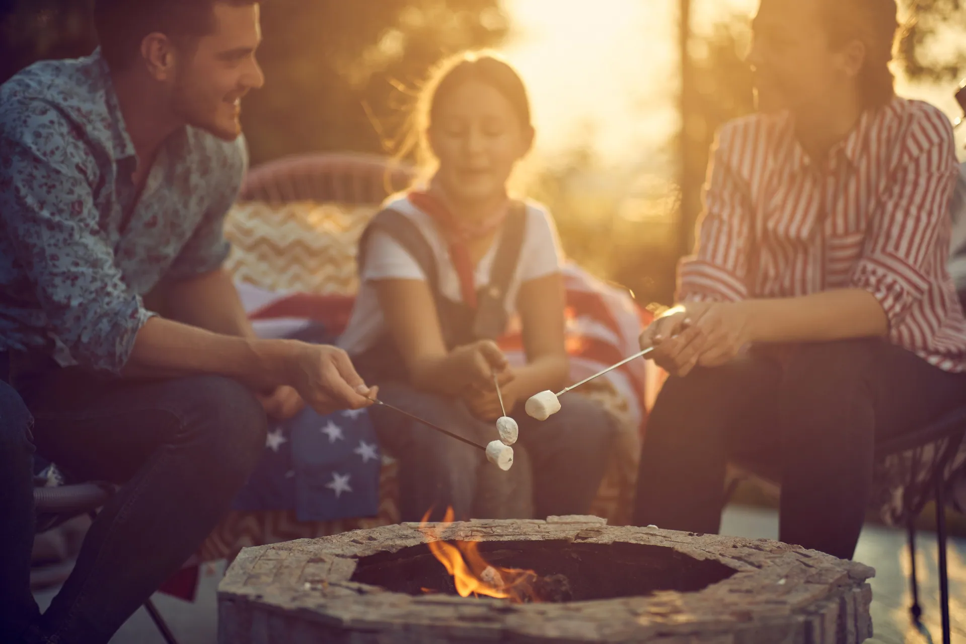 Family roasting marshmallows around a fire pit
