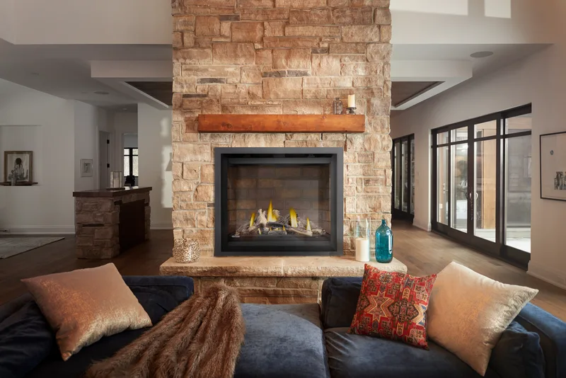 A gas fireplace in a light stone breast with a timber mantel