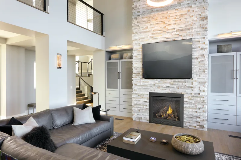 A gas insert in a stacked-stone chimney breast below a wall-mounted TV