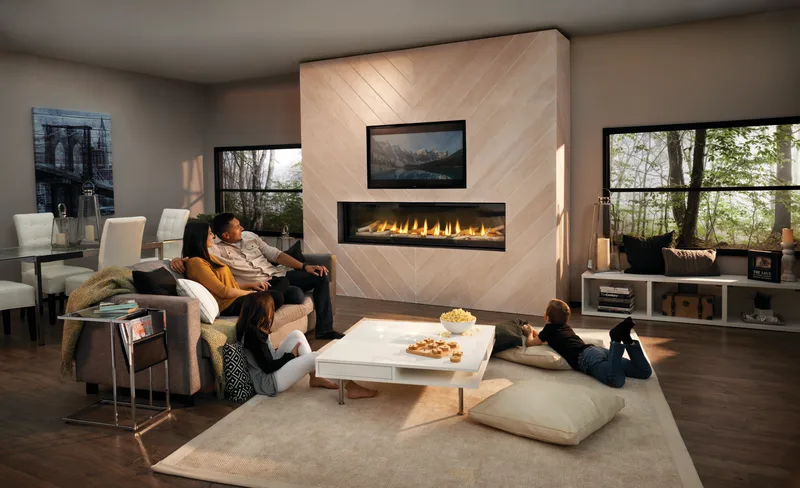 A family stretched out on the sofa and floor in front of a long linear gas fireplace