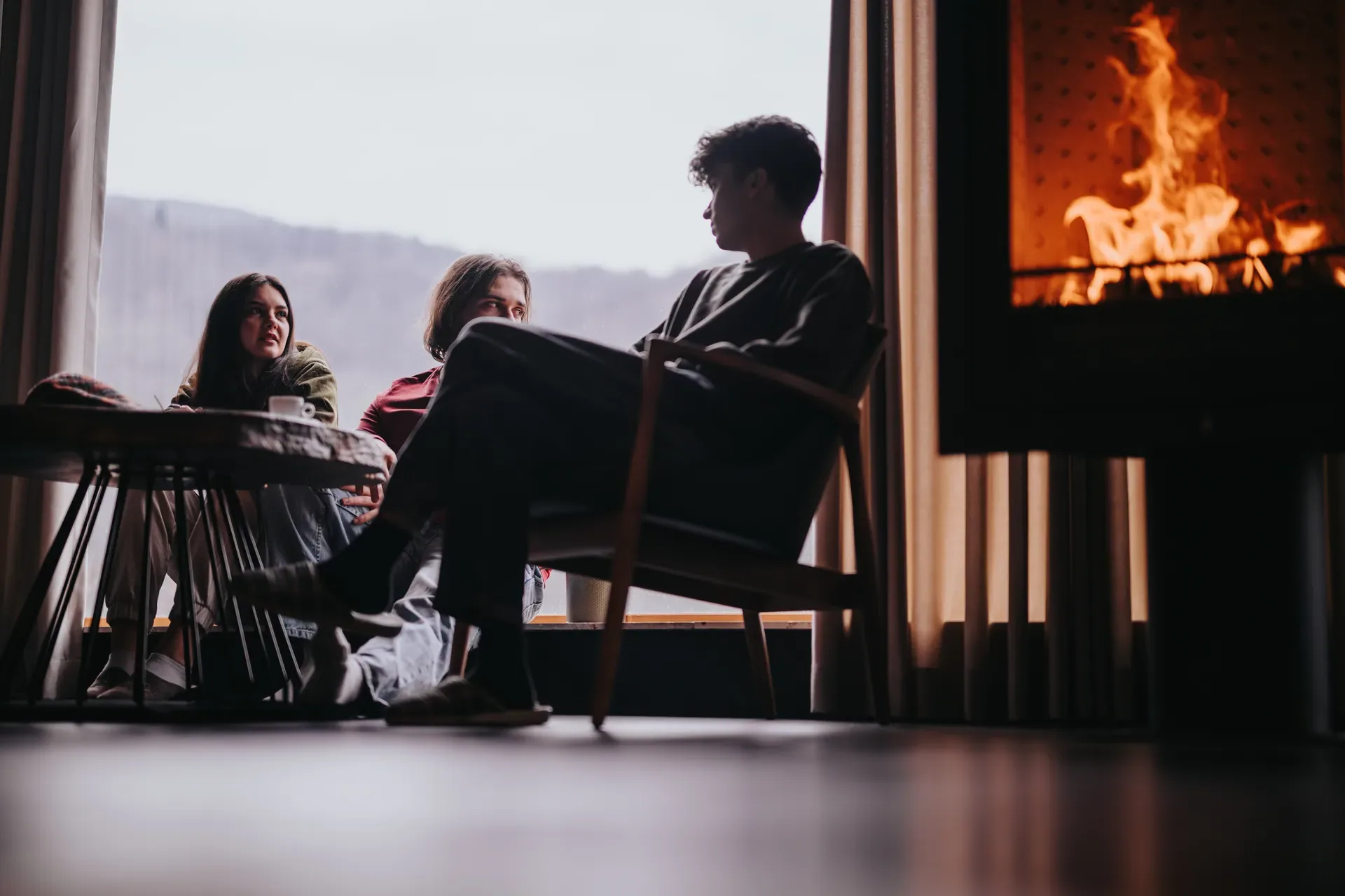 People seated by a large modern fireplace with a mountain view
