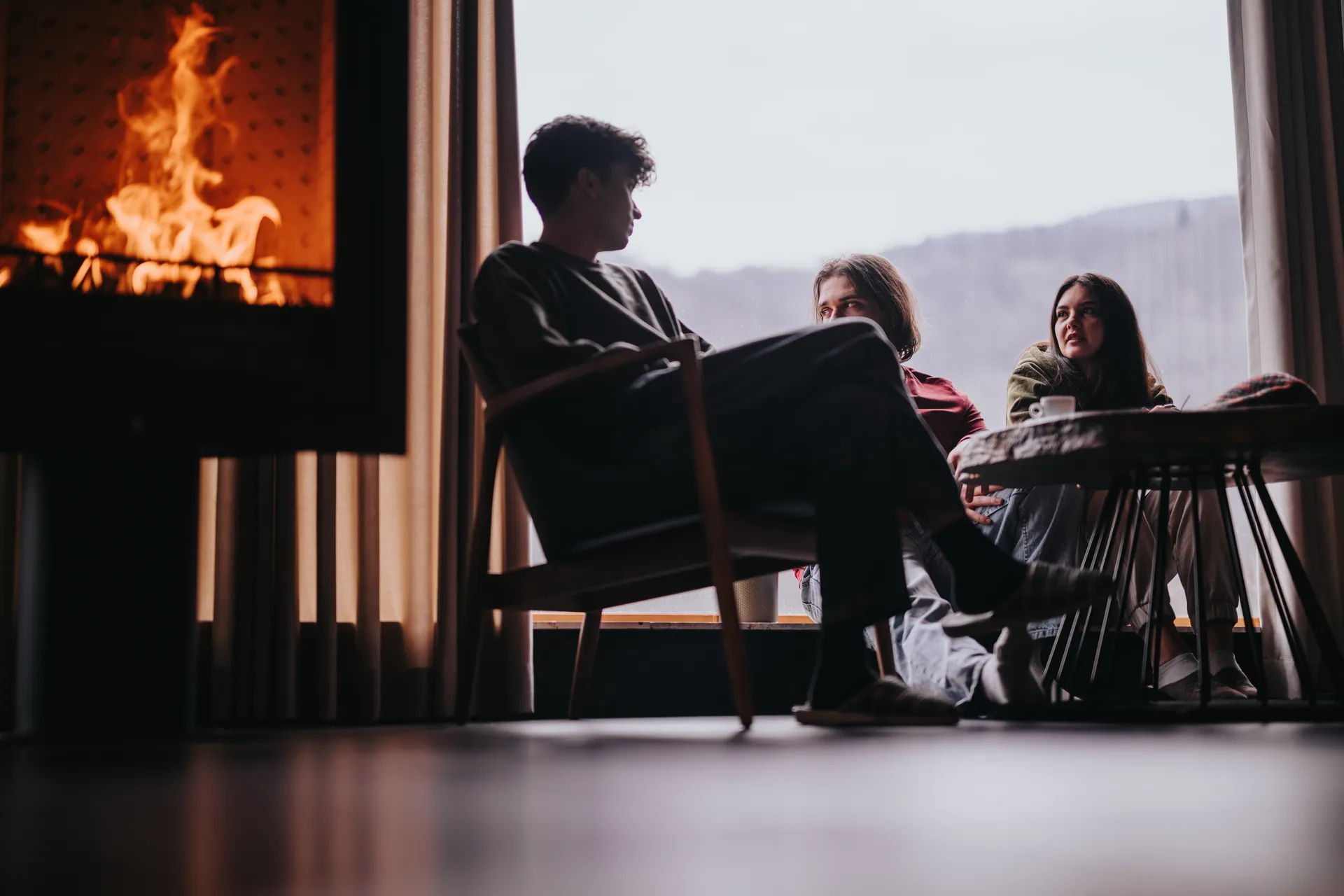 People seated by a large modern fireplace with a mountain view