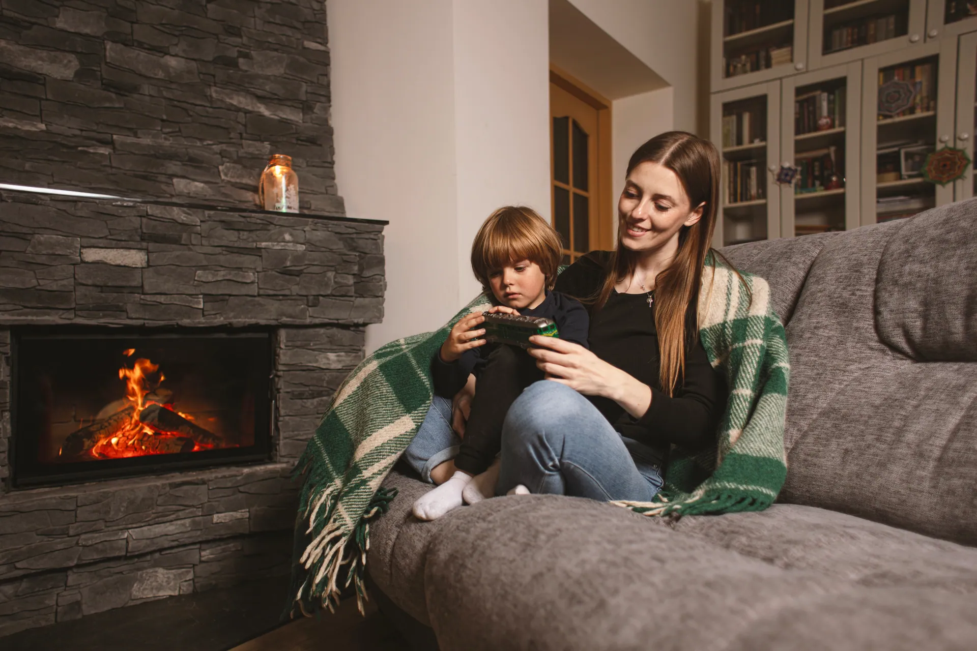 Mother and child on a sofa beside a modern linear stone fireplace