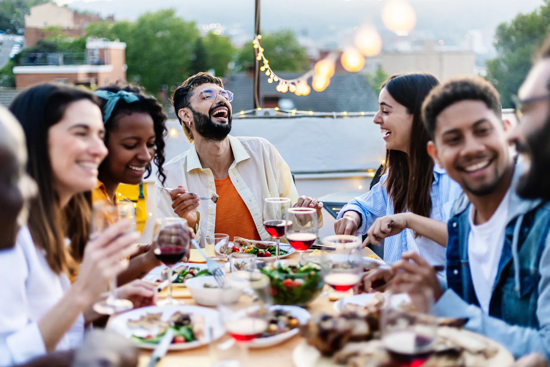 Friends around an outdoor dinner table under string lights
