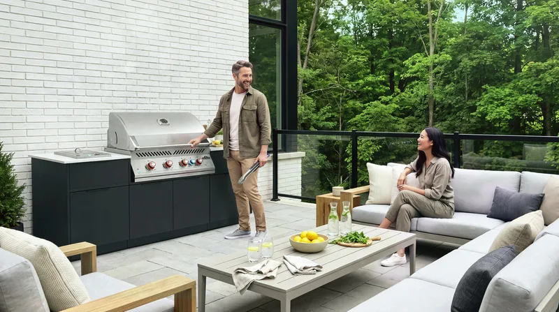 A man at a built-in grill on a covered patio while his partner sits nearby