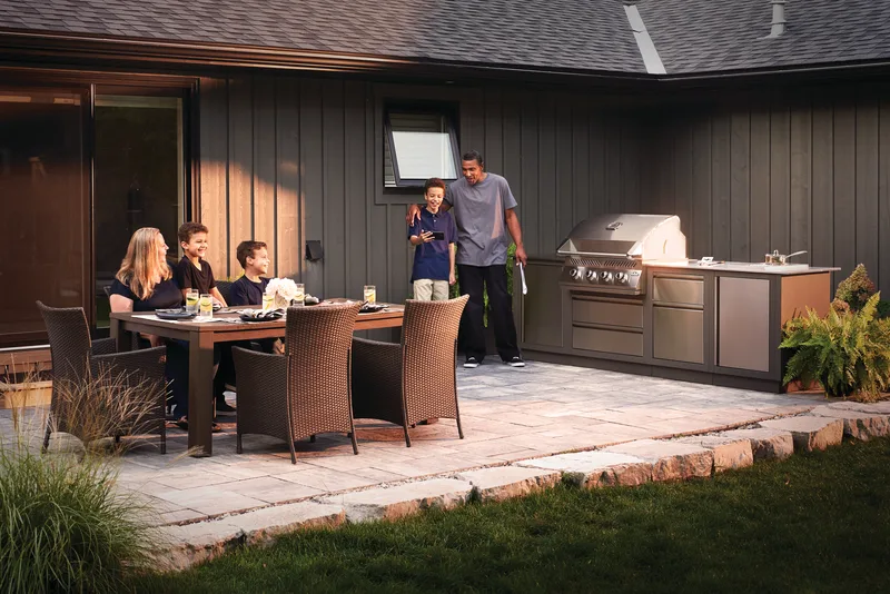 A group at a patio table beside a full outdoor kitchen at dusk