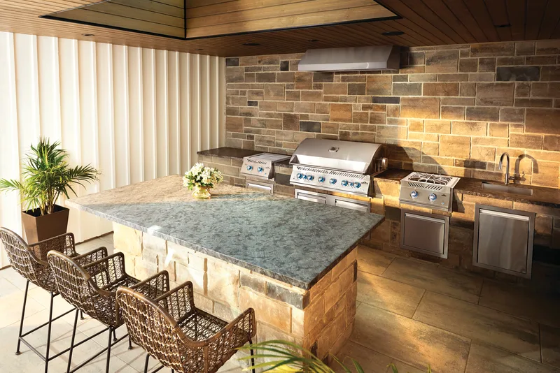 An outdoor kitchen island with two built-in grills and bar stools