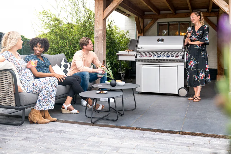 Friends gathered under a pergola beside a built-in grill run