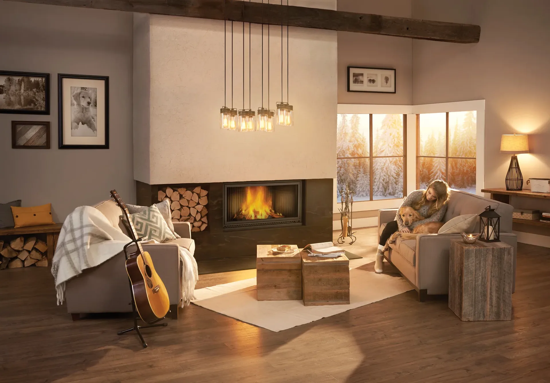 Woman and her golden retriever beside a lit wood fireplace, snowy pines outside