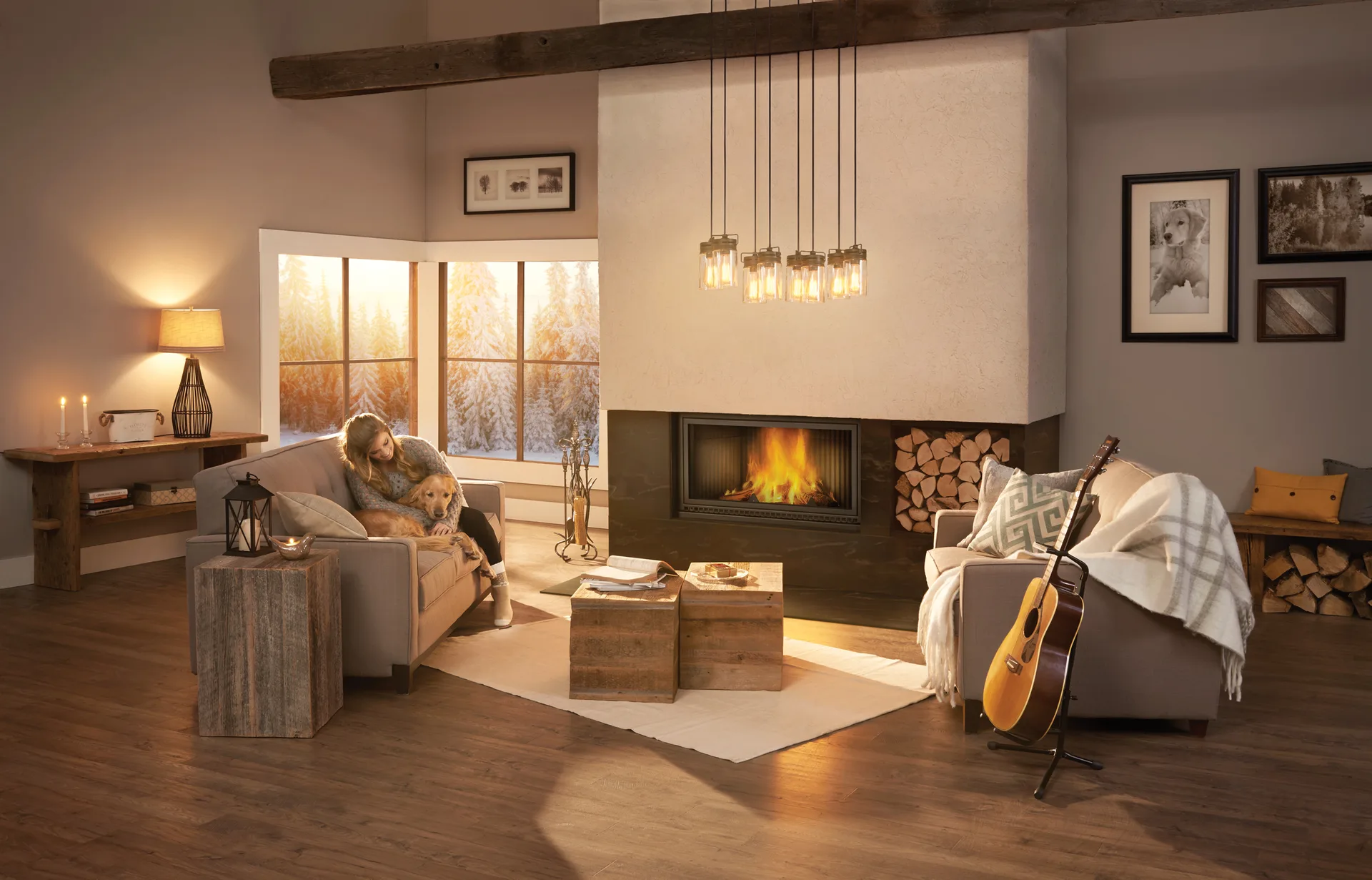 Woman and her golden retriever beside a lit wood fireplace, snowy pines outside